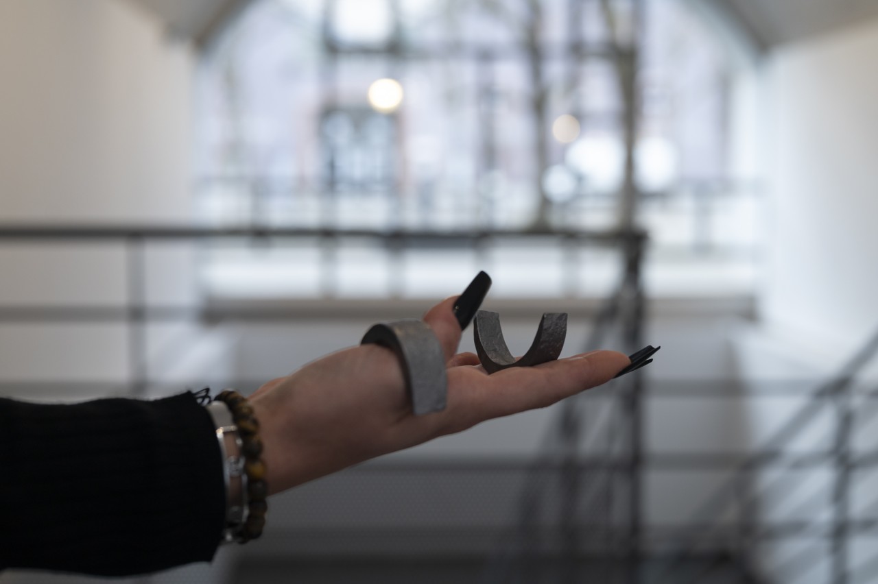 Une main tient des éléments métalliques qui peuvent sembler être des bijoux ou des prothèses