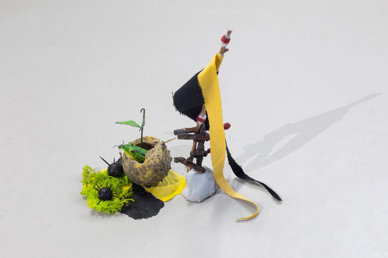 L'oeuvre est une petite sculpture de 30 centimètres de hauts. Elle est composée d'un étendard avec un drapeau chevaleresque et d'un recipient dans lequel loge une grenouille, avec des petits fléaux autours.