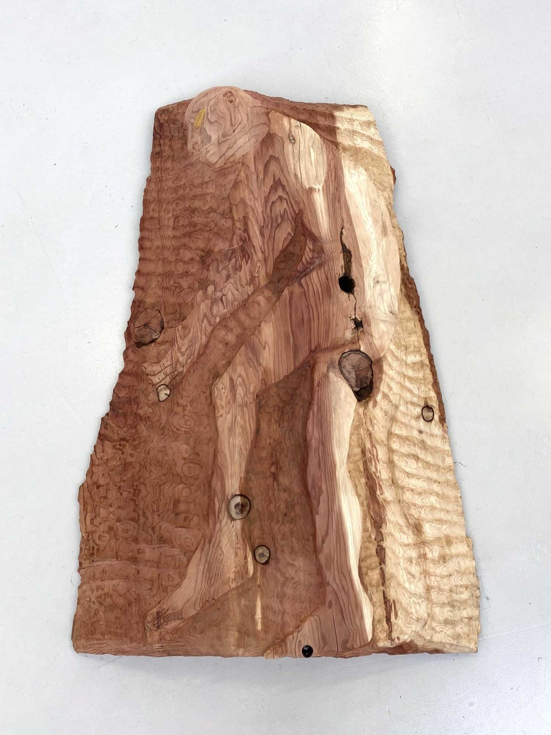 Bois de séquoia de 130 centimètres de haut pour 85 centimètres de large. Dans le bois est sculpté une figure humaine cueillant une fleur.