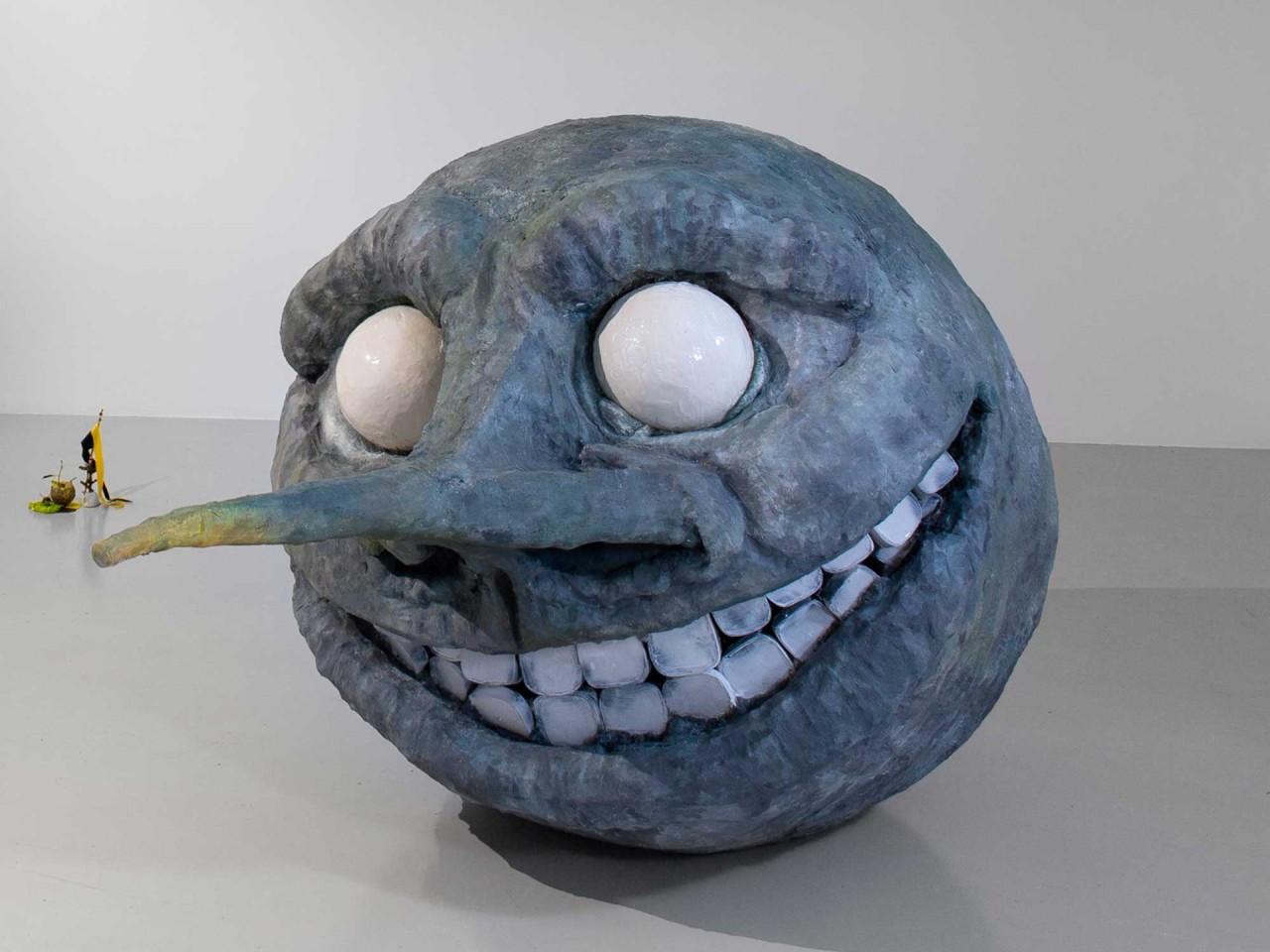 L'oeuvre est une sculpture imposante de 120 centimètres de haut pour 140 centimètres de largeur et 210 centimètres de longueur. Elle a la forme d'un Lune au visage humain, au nez long, aux yeux blanc et dotée d'un grand sourir laissant apparaître ses dents blanches.