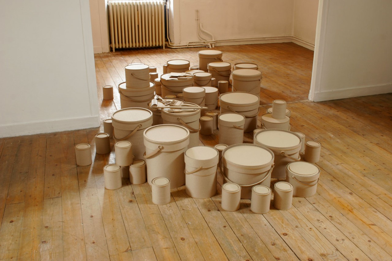 Paint pots of different sizes spread out on the floor