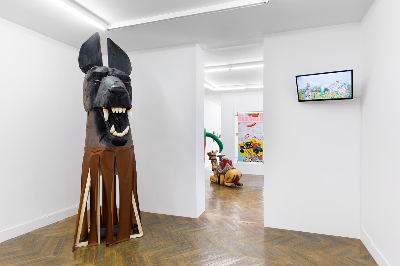 Photo représentant un espace d'exposition avec une sculpture d'un chien et un écran projetant une vidéo