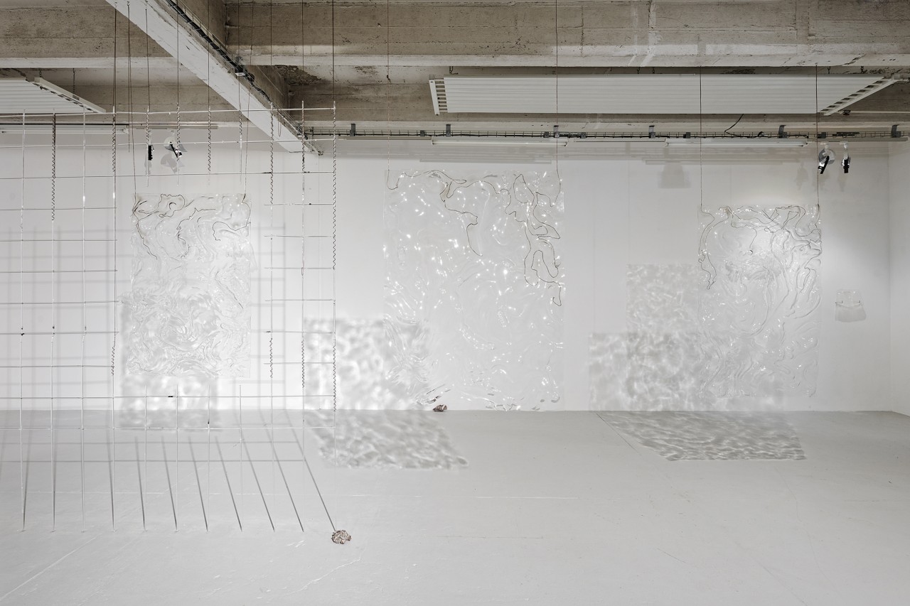 Des sculptures de verre en forme de grillage délimitent des espaces et constituent un espace flottant, évoquant un monde aquatique. Au sol, des sculptures évoquant des agrégats minéraux sont disposées, accompagnant les visiteurs dans leur déambulation et construisant une carte cosmique terrestre. Elen Hallégouët construit un parcours sensoriel, jouant avec la clarté et l’impression de réel.