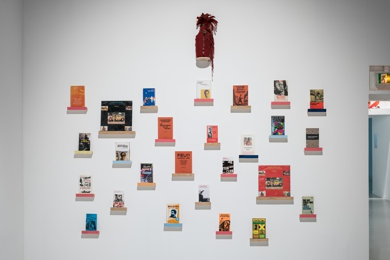 Collection de livres accrochés au mur sur des socles colorés