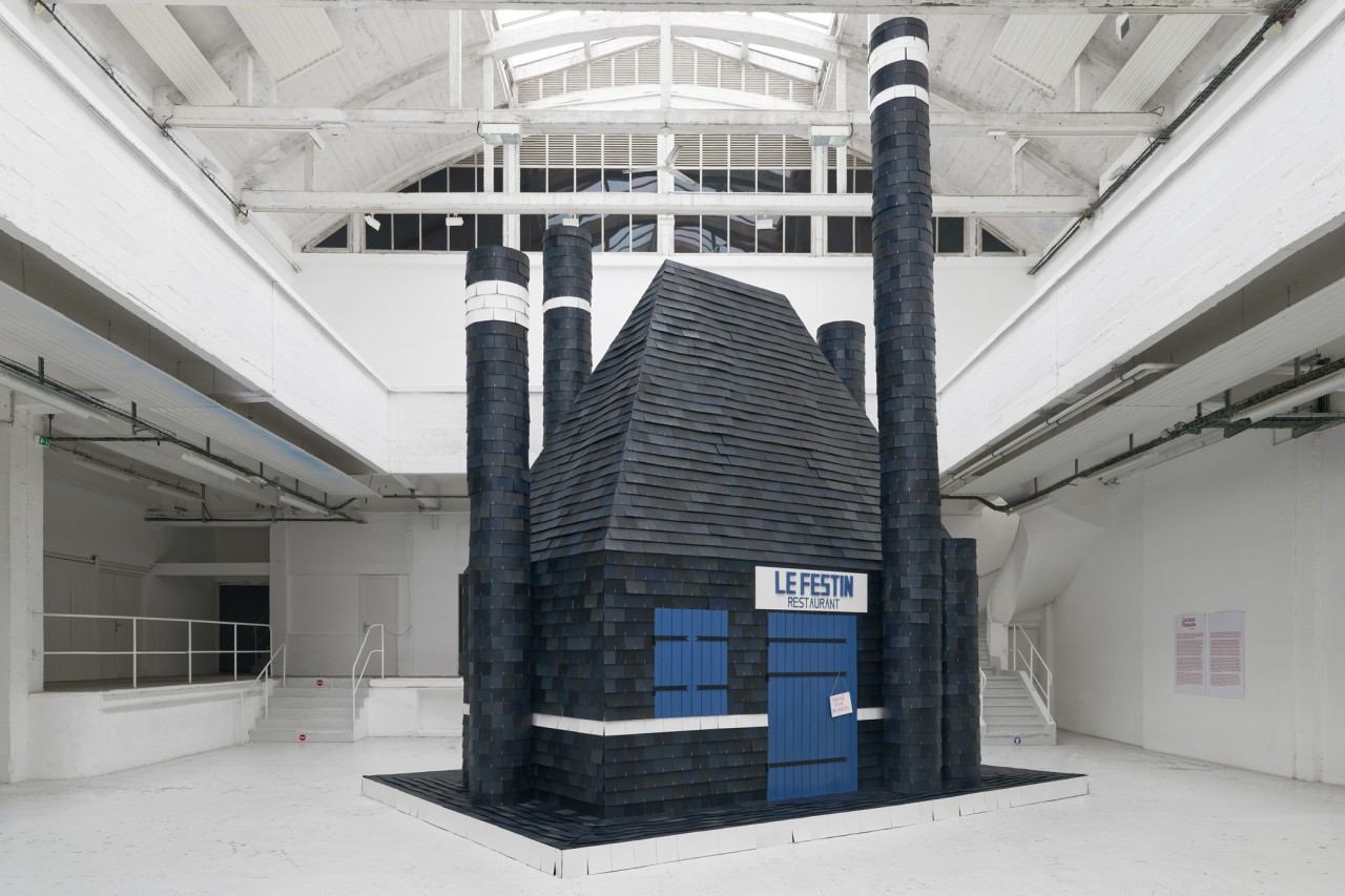 Une sculpture monumentale et monolithique investit le patio du centre d’art, mimant un restaurant bâti selon une architecture traditionnelle bretonne en ardoise. A là fois sublime et merveilleux, l’édifice- sculpture rappelle le monde des contes de fées tout en comportant cette part de drôlerie chère à l’artiste. Ce restaurant « fermé pour vacances » n’est pas accessible, il semble réel mais en s’approchant son caractère factice s’affirme.