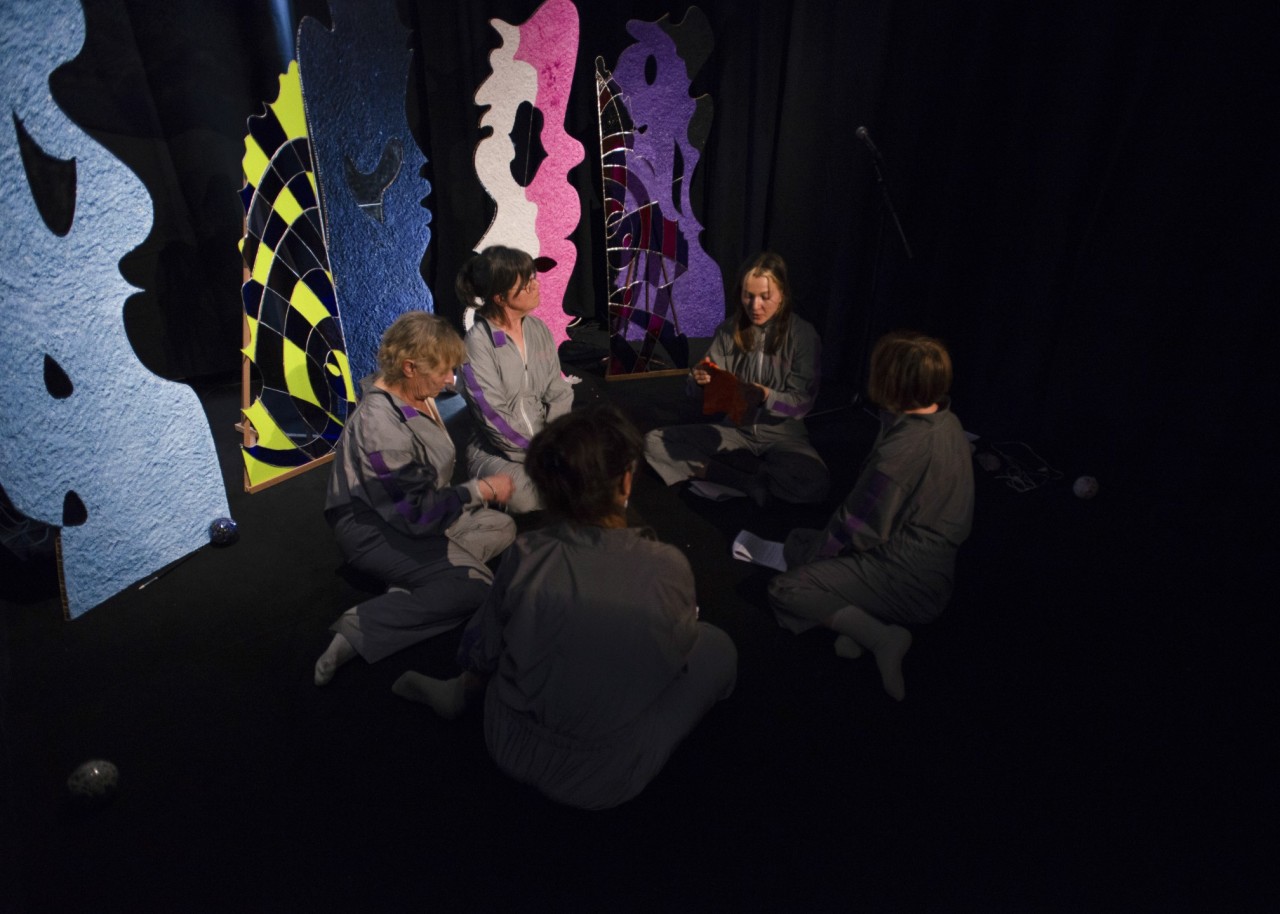 Groupe de femmes assises en tailleurs entourées de panneaux colorés