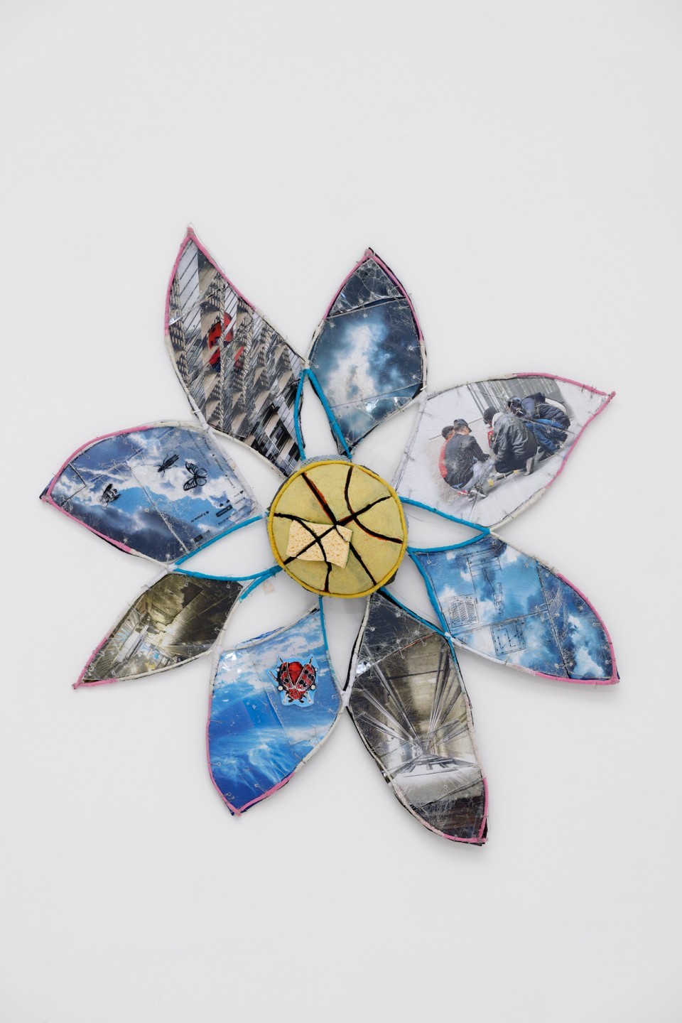 Marguerite est une œuvre caractéristique des assemblages d’Anna Solal. Si le cœur de la fleur est occupé par ce morceau de ballon, les pétales alternent entre des photographies de la ville (une vue d’immeuble du 11e arrondissement, de jeunes migrants déjeunant sur un trottoir à Pantin, une vue plongée d’une cage d’ascenseur…) et des images du ciel au cœur duquel des coccinelles et des papillons. Chaque élément est finement travaillé dans cette iconographie qui évoque l’urbanité du Grand Paris.