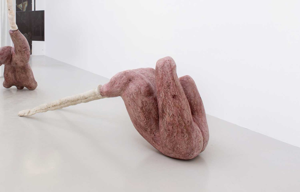 L'oeuvre est une sculpture rouge de forme humaine rouge, tordu et dont les jambes sont remplacées par des de grands pics blancs.