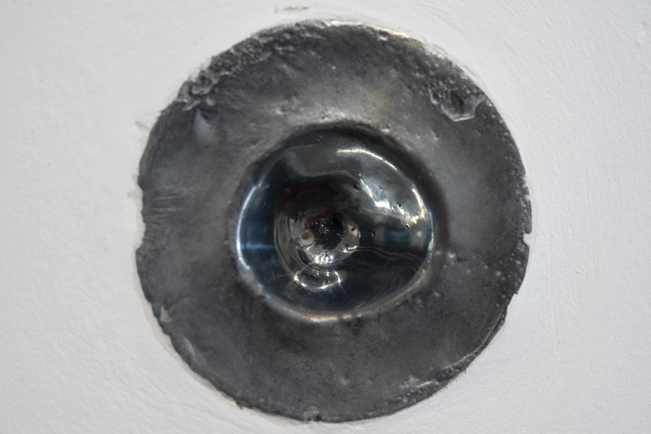 Une pièce métallique est dans le mur. Elle rappelle la forme d'un globe occulaire