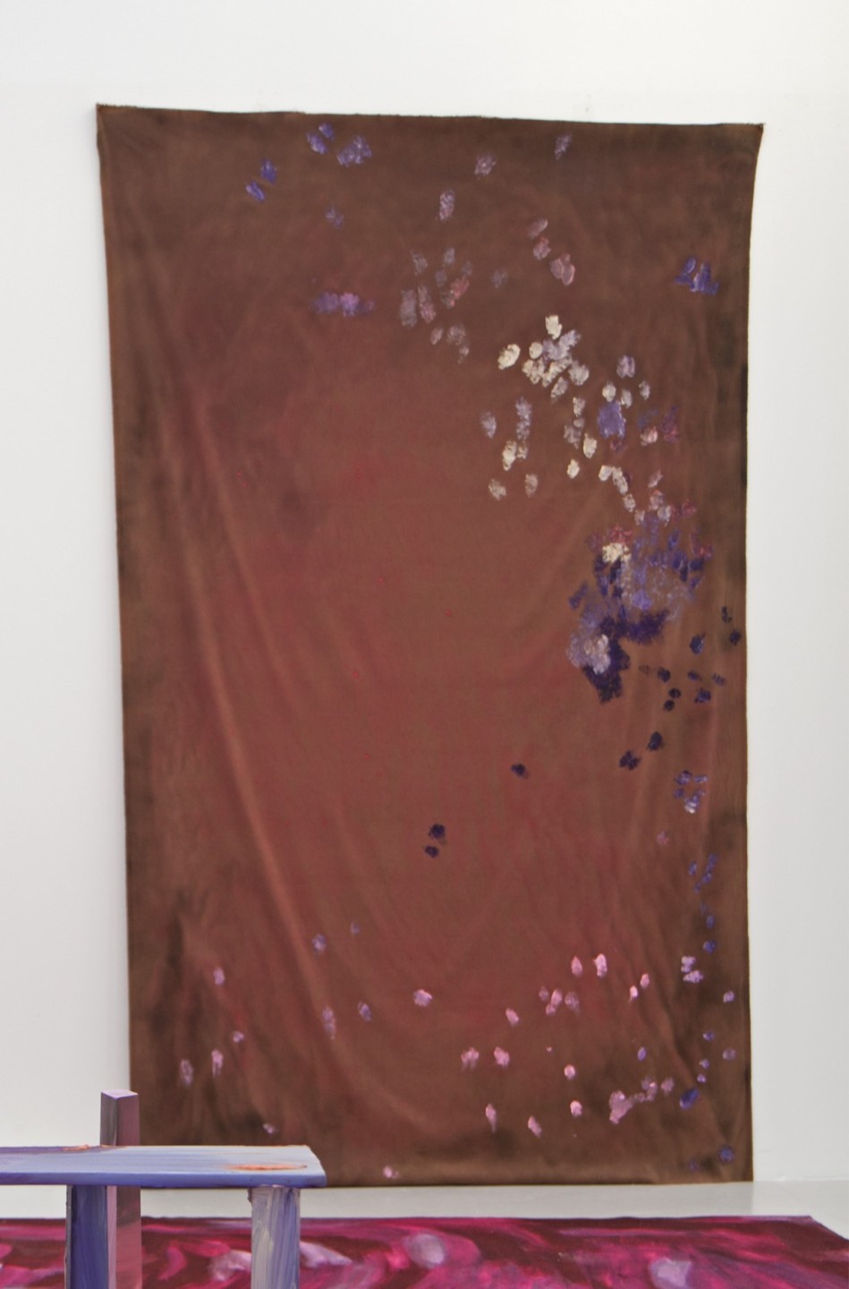L'oeuvre est un rideau marron et tacheté de peinture acrylique violet et jaune.