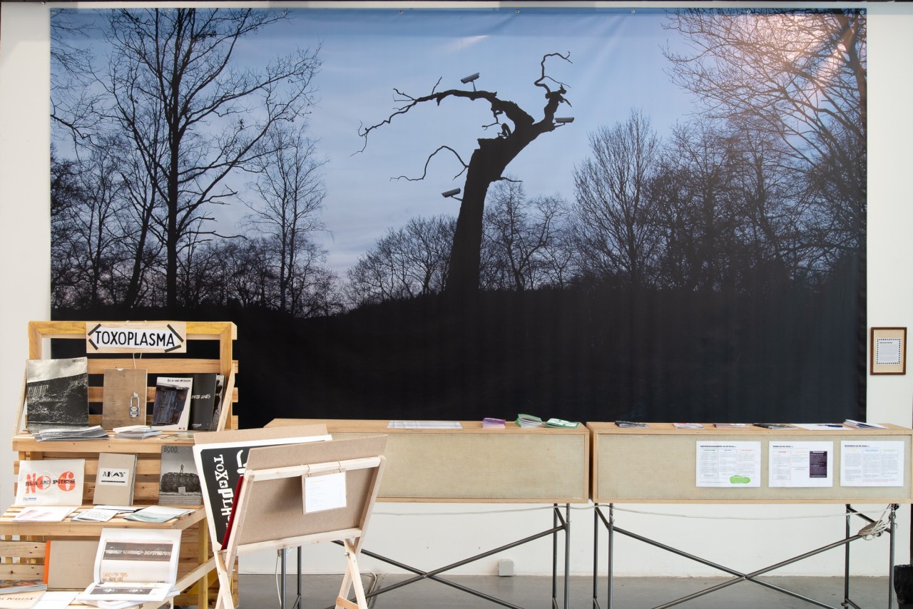 Photographie imprimée sur bâche représentant des caméras de surveillance installées de manière aléatoire sur les arbres d'une forêt